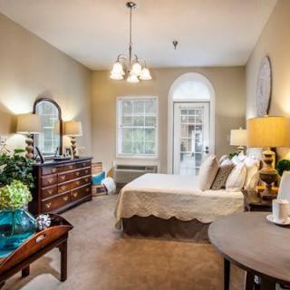 A cozy bedroom with a bed, dresser, and warm lighting.