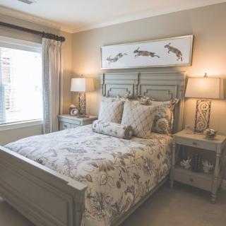 A cozy bedroom with a neatly made bed, featuring floral bedding and two bedside tables with lamps.
