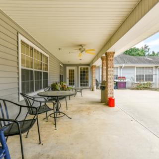 A spacious covered patio featuring chairs and a table, located at the back of a house.