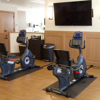 A modern gym area featuring two recumbent exercise bikes and a wall-mounted television.