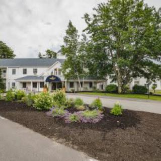 A picturesque hotel with a well-maintained garden and driveway.