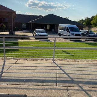 A view of a building with vehicles parked in front on a sunny day.