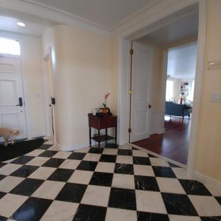 A stylish entrance with a black and white checkerboard floor and a small side table with decor.