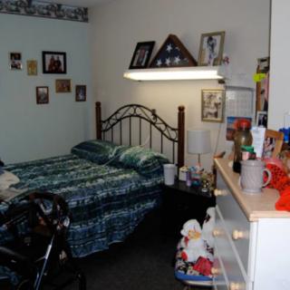 A cozy bedroom with a single bed, decorated with wall photos and personal items.