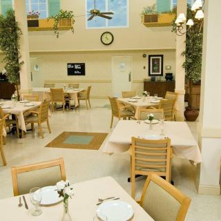 A well-lit dining area with neatly arranged tables and chairs, adorned with plants and decorative elements.