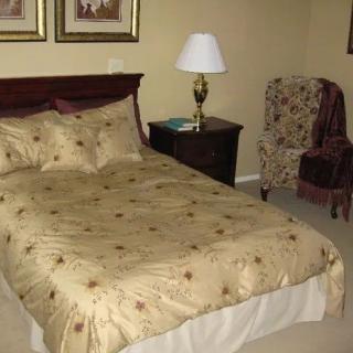 A cozy bedroom with a neatly made bed, nightstand, and lamp.