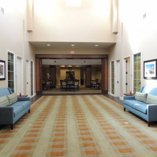 A modern lobby with sofas and a patterned carpet leading to another room.
