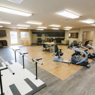 A spacious indoor fitness area equipped with various exercise machines and rehabilitation equipment.