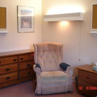 Cozy living room corner with an armchair and dresser.