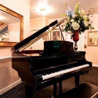 A grand piano elegantly situated in a well-decorated interior with a floral arrangement on top.