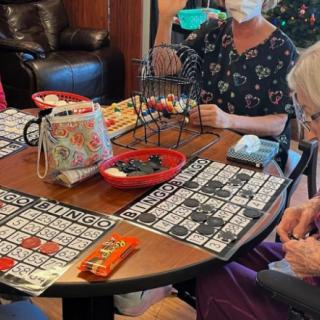 A group of elderly people playing bingo at a table.