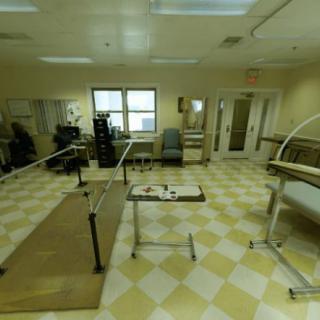 A therapy room equipped with parallel bars and medical equipment for rehabilitation exercises.