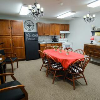 A cozy dining area with a table set for a meal, surrounded by wooden chairs and kitchen cabinets.