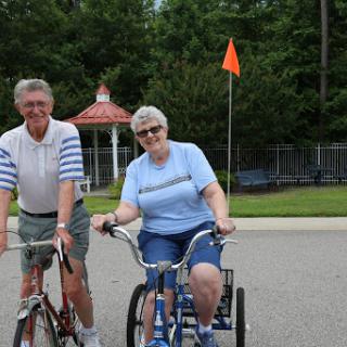 An elderly couple enjoying a sunny day cycling together.