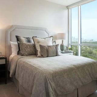 A modern and cozy bedroom with neutral tones, featuring a large window offering a scenic view.
