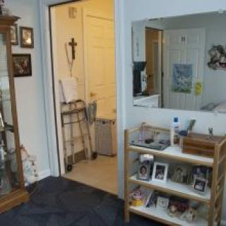 A cozy living room featuring a shelf with various items, a mirror, and an open doorway.