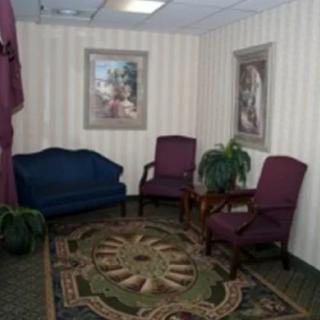 A cozy waiting room with a sofa, two chairs, a decorative rug, and framed artwork on the walls.