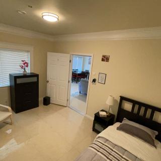 A cozy, minimalist bedroom with a bed, lamp, and window, featuring simple decor.