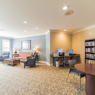 A cozy lounge area featuring comfortable seating, computer stations, and a small library.