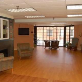 A spacious modern living room with wood flooring, featuring comfortable seating and large windows.