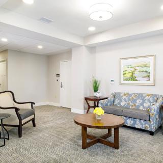 A cozy living room with a sofa, armchair, coffee table, and decorative artwork.