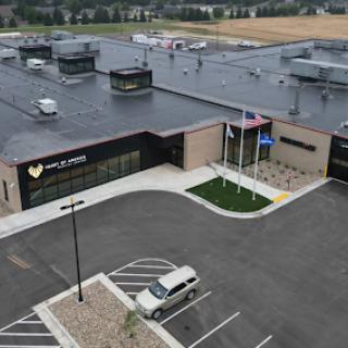 A modern healthcare facility featuring a sleek design, surrounded by a spacious parking lot.