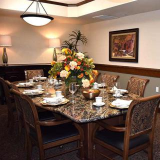 A formal dining room with a decorated table set for a meal, featuring floral arrangements and elegant furnishings.