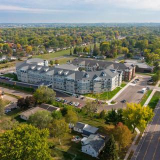 Aerial view of a residential building surrounded by trees and roads in an urban area.