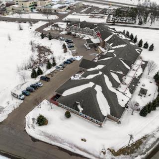 An aerial view of a snow-covered building with a parking lot, showcasing the serene winter landscape.