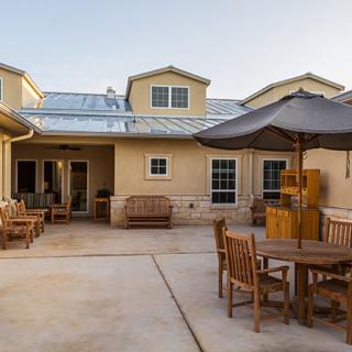 A spacious patio with outdoor furniture and an umbrella in front of a modern house.
