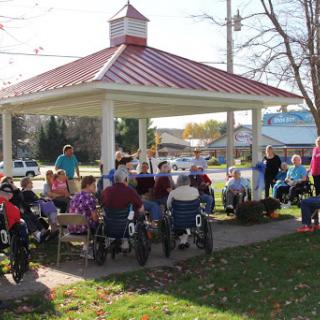 A vibrant community gathering at a park pavilion, featuring elderly individuals enjoying the outdoors.