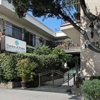The entrance to a residential building with lush greenery and a welcoming sign.