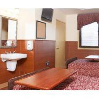 A small hotel room with a bed, sink, and television.