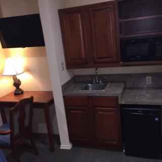 A small hotel room kitchenette with a desk, television, and basic amenities.