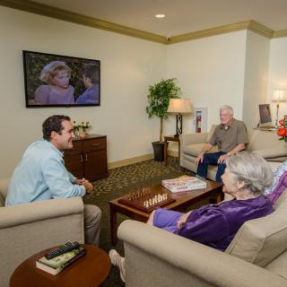 A group of people enjoying a conversation in a cozy living room while watching TV.