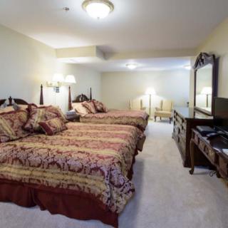 A hotel room featuring two large beds with ornate bedding and classic wooden furniture.