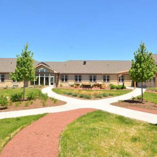 A scenic view of a building with landscaped pathways and greenery under a clear blue sky.