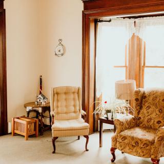 A cozy vintage-style living room with upholstered armchairs and a large window.