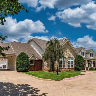 A suburban house with a landscaped front yard and a cloudy blue sky.