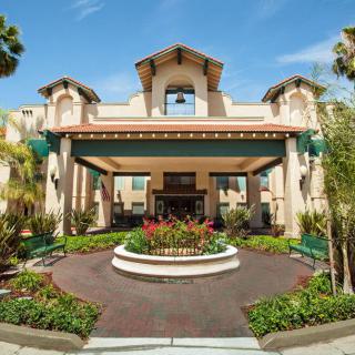 A grand hotel entrance surrounded by lush landscaping and palm trees.