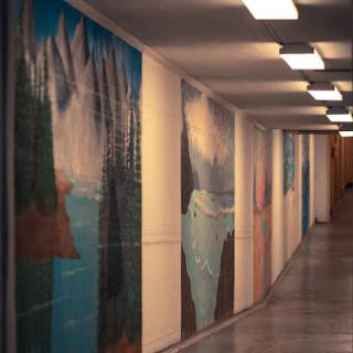 A corridor adorned with vibrant murals, illuminated by overhead lighting.