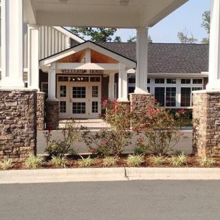 A well-designed building entrance with stone columns and landscaped surroundings.