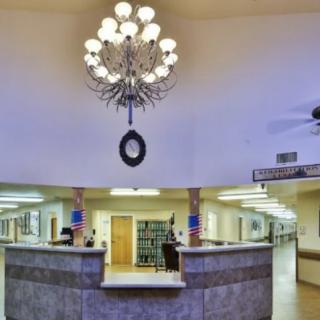 A well-lit reception area with a large chandelier and a central desk.
