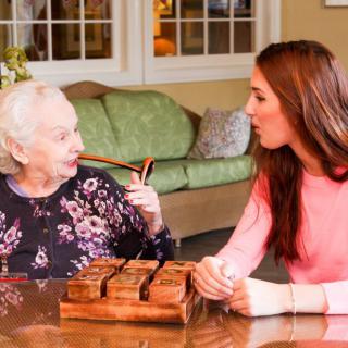 An elderly woman and a young woman engaging in a warm conversation at home.
