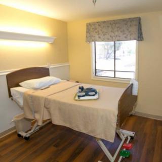 A hospital room with a single bed and a window providing natural light.