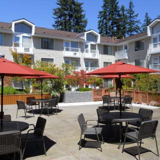 Outdoor courtyard with tables, chairs, and red umbrellas in a residential complex.
