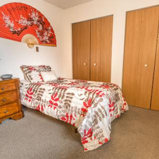 A cozy bedroom featuring a patterned bedding set, wooden furniture, and decorative wall art.