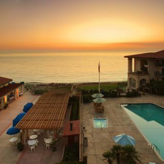 A serene beachfront resort with a pool overlooking a beautiful sunset.