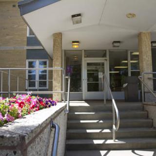 Entrance of a building with steps, railing, and flowers.