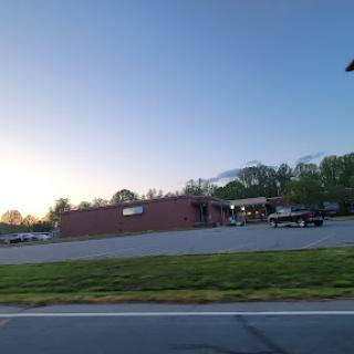 A serene view of a building at sunset, with parked vehicles in the foreground.